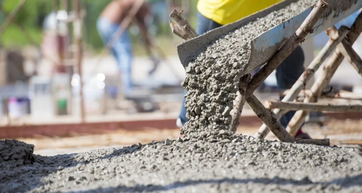 Wet concrete pouring from a chute onto a prepared slab