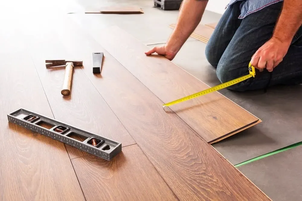 Hire flooring estimating services: laminate floorboards being laid with tape measure and spirit level