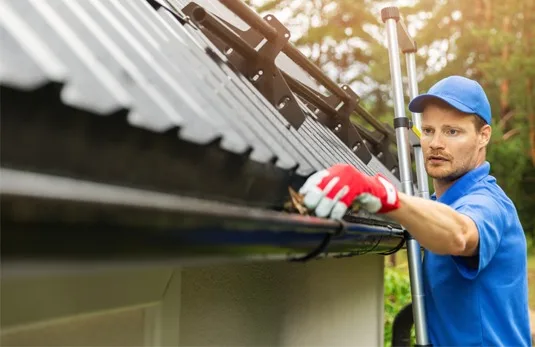 A worker fitting guttering along the edge of a roof