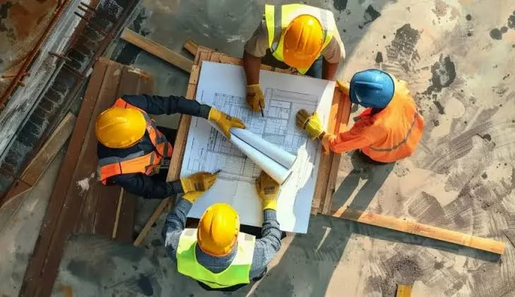 earthwork estimating services: four workers reviewing site plans together on a construction site